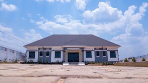 A modern building with a flat roof and a symmetrical facade, featuring a central entrance with steps leading up to it. - Gibson Motel (Mbarara)