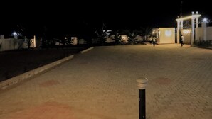 A paved pathway leading to a gated entrance at night. - Gibson Motel (Mbarara)