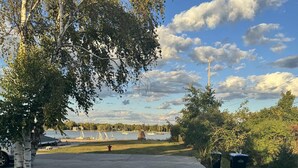 A pathway leading to a grassy area with trees and a view of boats on a body of water. - Wake up to breathtaking sunrise views from the porch of this 2 BR waterview home (Sturgeon Bay)