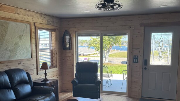 A spacious living room with a leather couch, a wooden coffee table, and a black armchair. - Wake up to breathtaking sunrise views from the porch of this 2 BR waterview home (Sturgeon Bay)