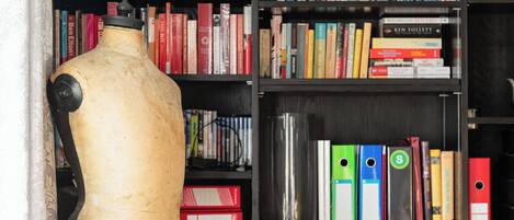 Un mannequin se tient devant une bibliothèque remplie de livres et de classeurs.