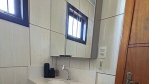 A bathroom with a white sink, a mirror above it, and a wooden door. - Ape in the mountains (Caxias do Sul)