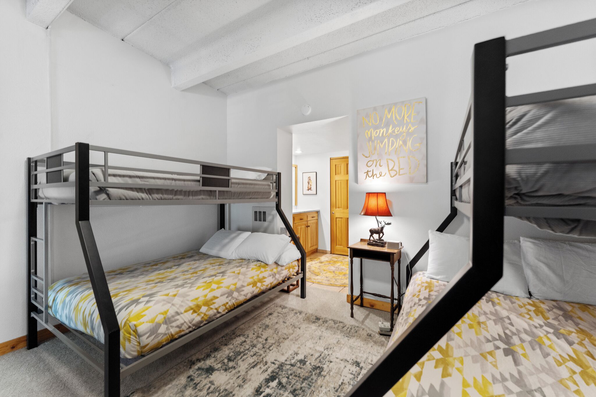 Una habitación con literas, una mesita con lámpara y una pared con una cita motivacional.