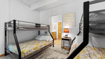 Una habitación con literas, una mesita con lámpara y una pared con una cita motivacional.