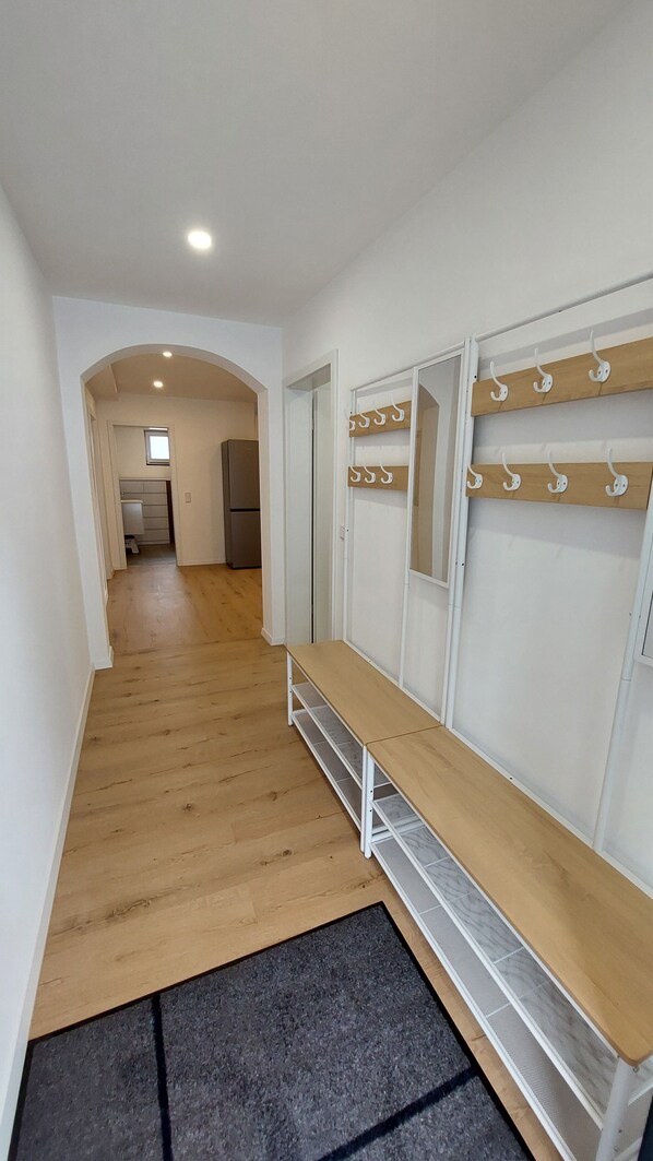 A hallway with a wooden bench, coat hooks, and a small window. - New modern apartment "Gerda" for up to 6 people (Mörlenbach)