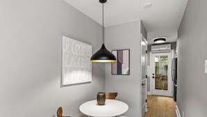 Un comedor moderno con una mesa redonda blanca, una lámpara colgante negra y sillas de madera.