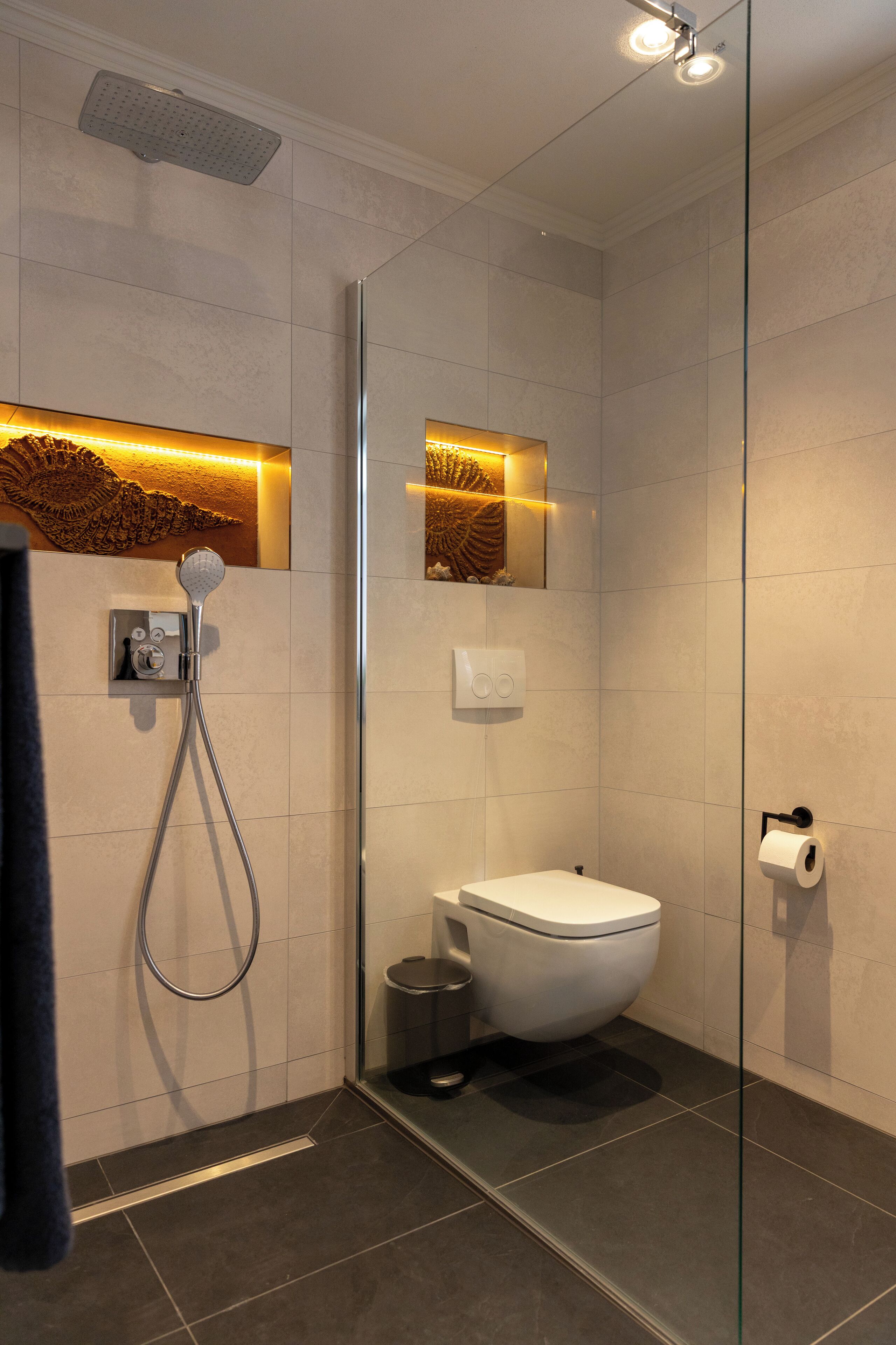Ein modernes Badezimmer mit Duschkabine aus Glas, Toilette und Mülleimer.