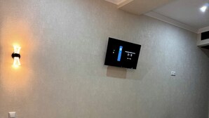 Habitación de hotel con una cama, un televisor de pantalla plana en la pared y una mesita con un teléfono.