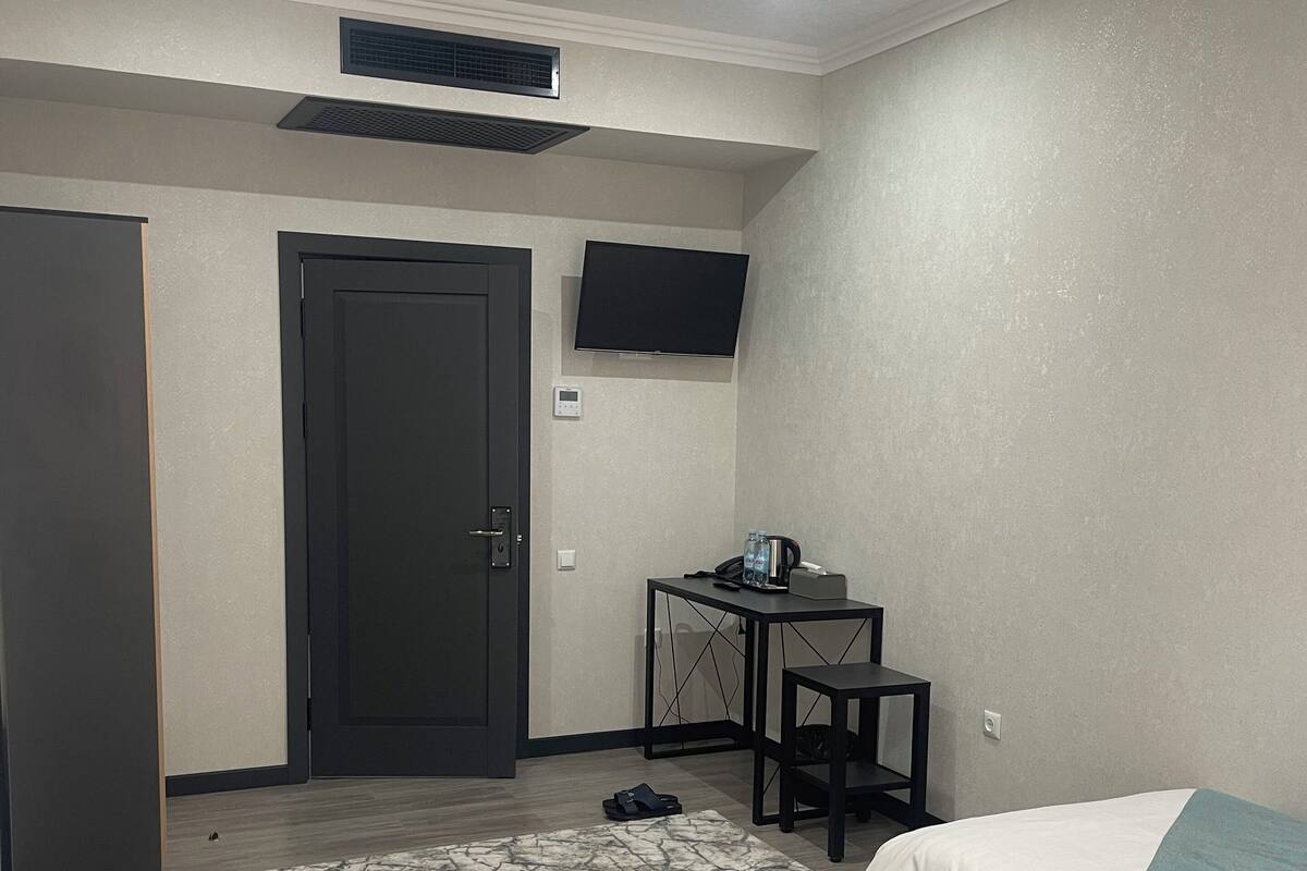 Una habitación de hotel con dos camas, un escritorio, un televisor y una puerta.