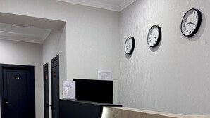 Un área de recepción con un mostrador, dos relojes de pared y una puerta con el número 25.