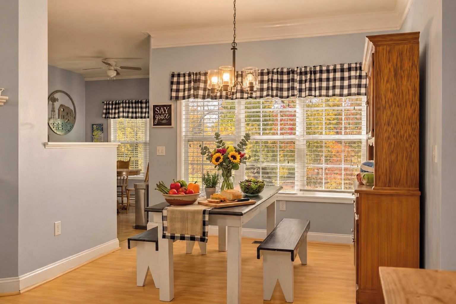 A kitchen with a dining table, bench seating, a chandelier, and a window with a view of trees.