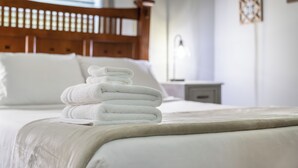 A neatly made bed with a stack of white towels, a wooden headboard, and a bedside table with a lamp. - Grove Hill - Spacious Home w/Hot Tub, 4 BRs, 4BAs, near downtown Dahlonega! (Dahlonega)