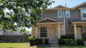 A two-story house with a front porch, a stone foundation, and a well-maintained lawn. - Modern 3BR by Park, Sleeps 8, 1Gig Wi-Fi, Garage Parking (Pflugerville)
