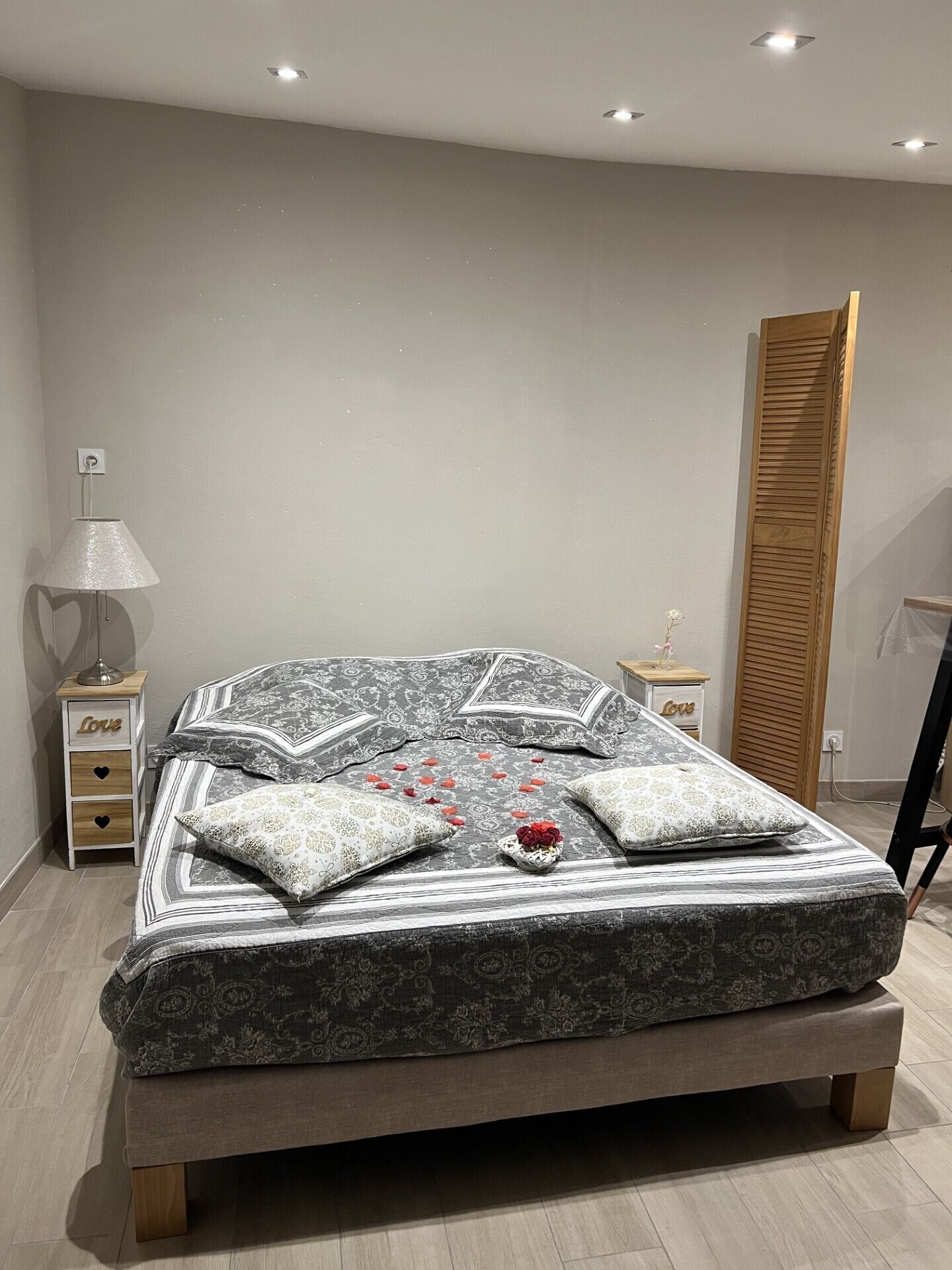 Une chambre moderne avec un grand lit, deux tables de chevet, une lampe et une armoire en bois.