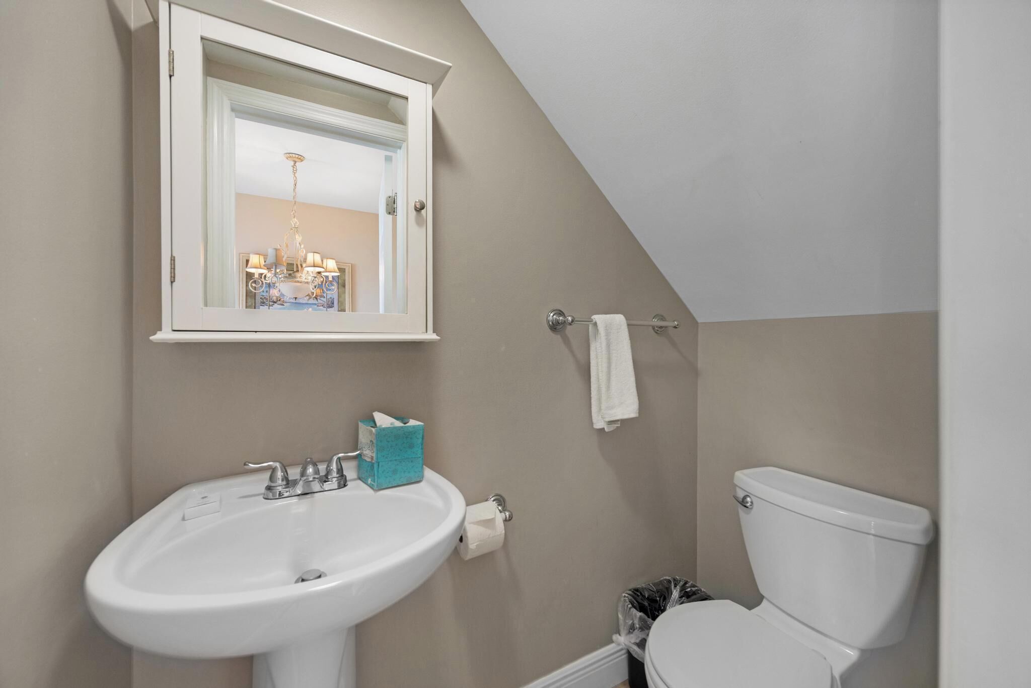 Une salle de bain avec un lavabo blanc, des toilettes et un miroir au-dessus du lavabo.