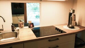 Una cocina con estufa integrada, un lavamanos y una ventana con vistas al verdor.