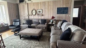 A living room with a wooden paneled wall, a sofa, a chair, and a coffee table. - Luxury on the Lake (Storm Lake)