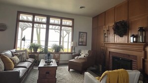 A living room with a fireplace, a sofa, a chair, and a coffee table. - Luxury on the Lake (Storm Lake)
