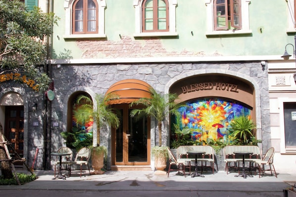 A hotel entrance with a stone facade, arched windows, and a colorful stained glass window.