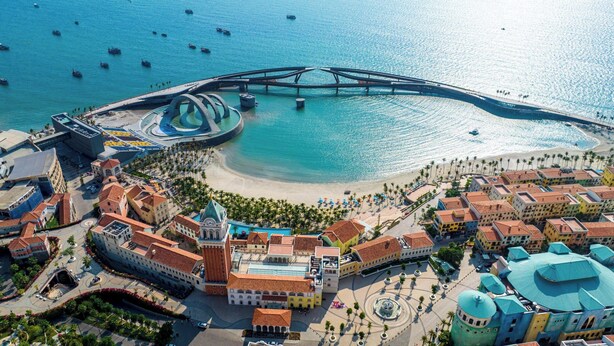 An aerial view of a coastal town with a prominent bridge, a central plaza, and a beach area. - BLESSED Hotel Phu Quoc (Phu Quoc)
