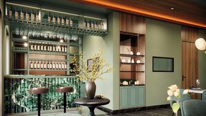 A bar area with shelves of bottles and glasses, a vase with flowers, and a seating area with a table and chairs. - BLESSED Hotel Phu Quoc (Phu Quoc)