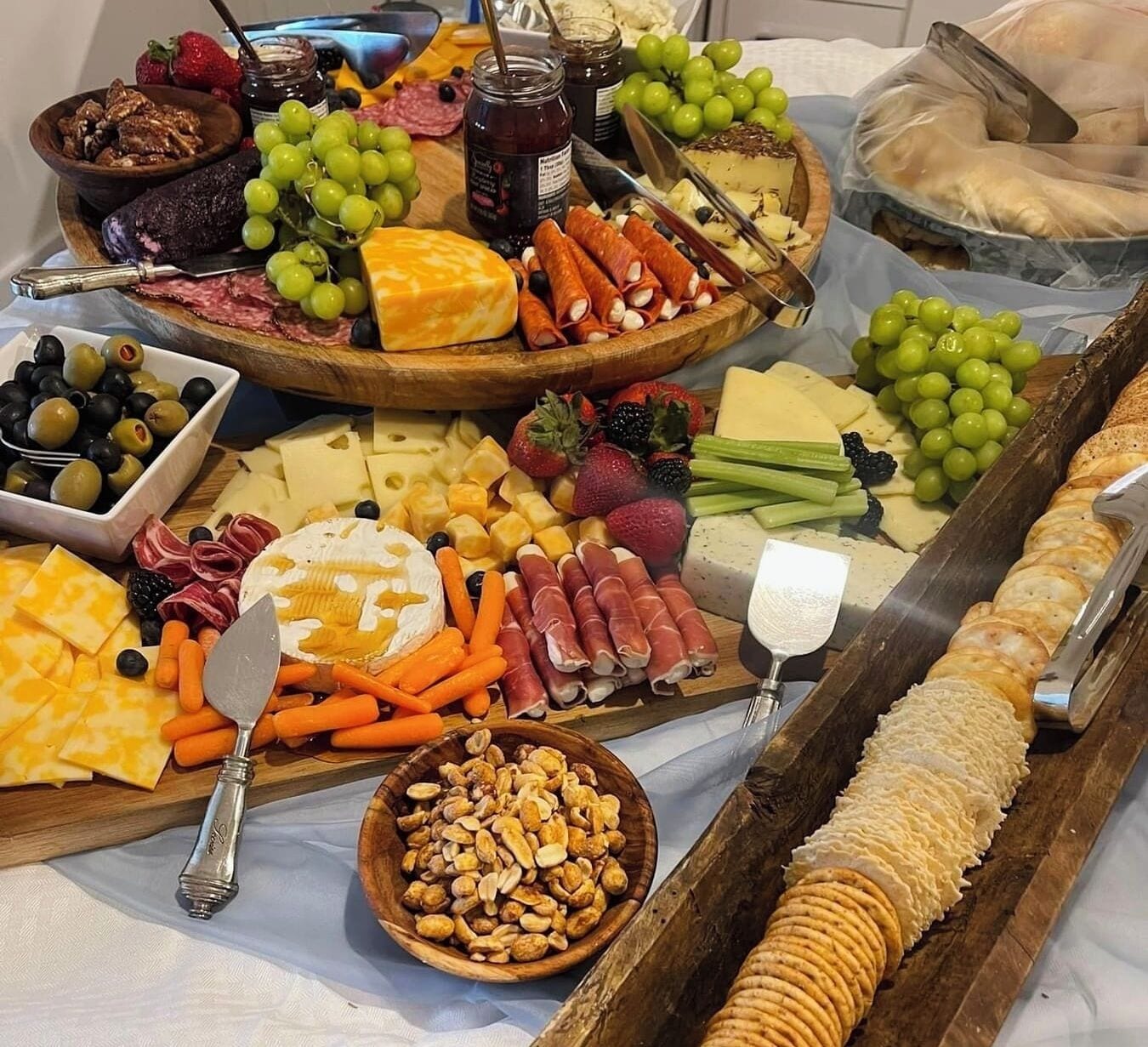 A variety of cheeses, cured meats, fruits, and nuts arranged on a wooden board.