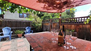 A patio with a table set for a meal, surrounded by a wooden fence and a blue chair.