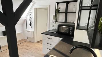 Een koffiezetapparaat/waterkoker, kookgerei, borden en bestek, eettafels