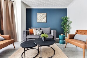 Ein modernes Wohnzimmer mit einer Couch, zwei Couchtischen und einer Topfpflanze.
