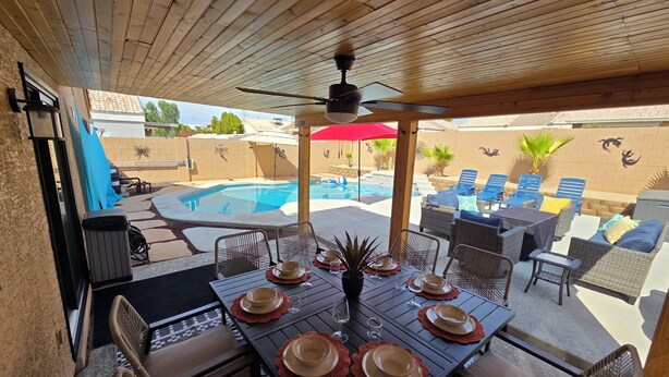 Eine Außenpatio mit Pool, Esstisch gedeckt mit Tellern und Gläsern, und Liegestühle.