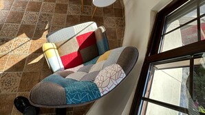 A high-ceiling room with a curved layout, a sofa with patterned cushions, a small white table, and a view through large windows.