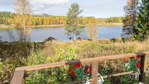 A lakeside view with a wooden deck and red flowers in the foreground.