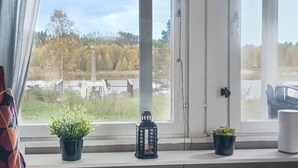 A room with a large window, a potted plant, a lantern, and a white device on the windowsill.