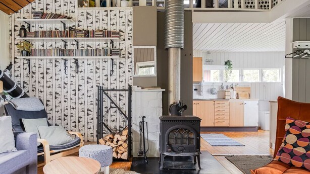 A cozy living room with a fireplace, a bookshelf, a comfortable sofa, and a dining area.