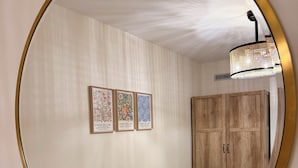 A hallway with a round mirror, wooden wardrobe, and three framed artworks on the wall. -  Comfort & Convenience Near Endless Local Amenities (Langley Township)