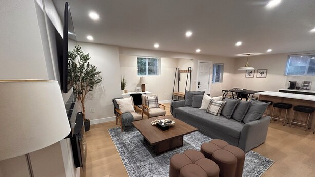 A modern living room with a grey sofa, a coffee table, and a TV mounted on the wall. -  Comfort & Convenience Near Endless Local Amenities (Langley Township)