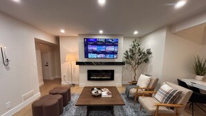 A modern living room with a flat-screen TV, a fireplace, and comfortable seating. -  Comfort & Convenience Near Endless Local Amenities (Langley Township)