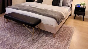 A neatly arranged bedroom with a bed, bedside tables, a bench, and a painting on the wall. -  Comfort & Convenience Near Endless Local Amenities (Langley Township)