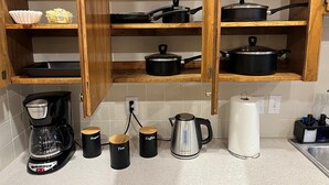 A kitchen with wooden cabinets, a coffee maker, and three labeled containers for sugar, tea, and coffee.