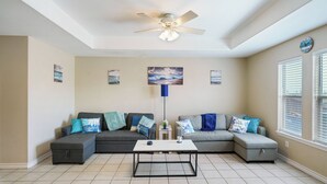 A living room with a sectional sofa, a coffee table, and a ceiling fan.