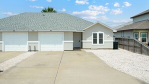 A two-story house with a garage, a covered porch, and a small attached building with a window.