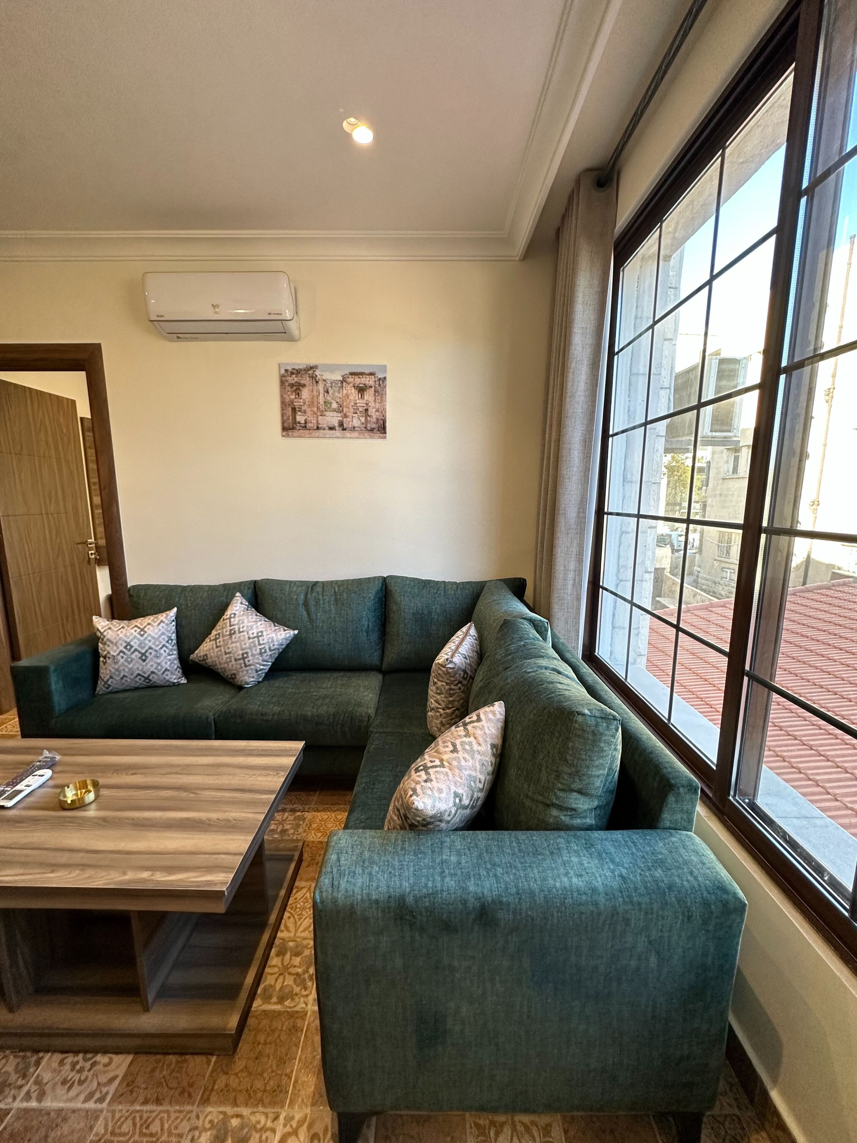 A living room with a sectional sofa, a coffee table, and a large window with a view of buildings.