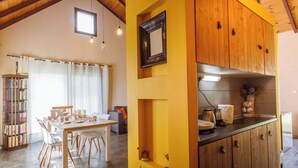 A kitchen with wooden cabinets, a dining area with a table and chairs, and a bookshelf.