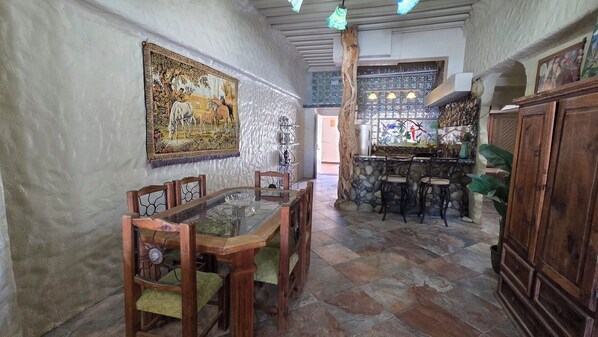 Un comedor con una mesa de vidrio y sillas de madera, una pared de piedra y un cuadro en la pared.