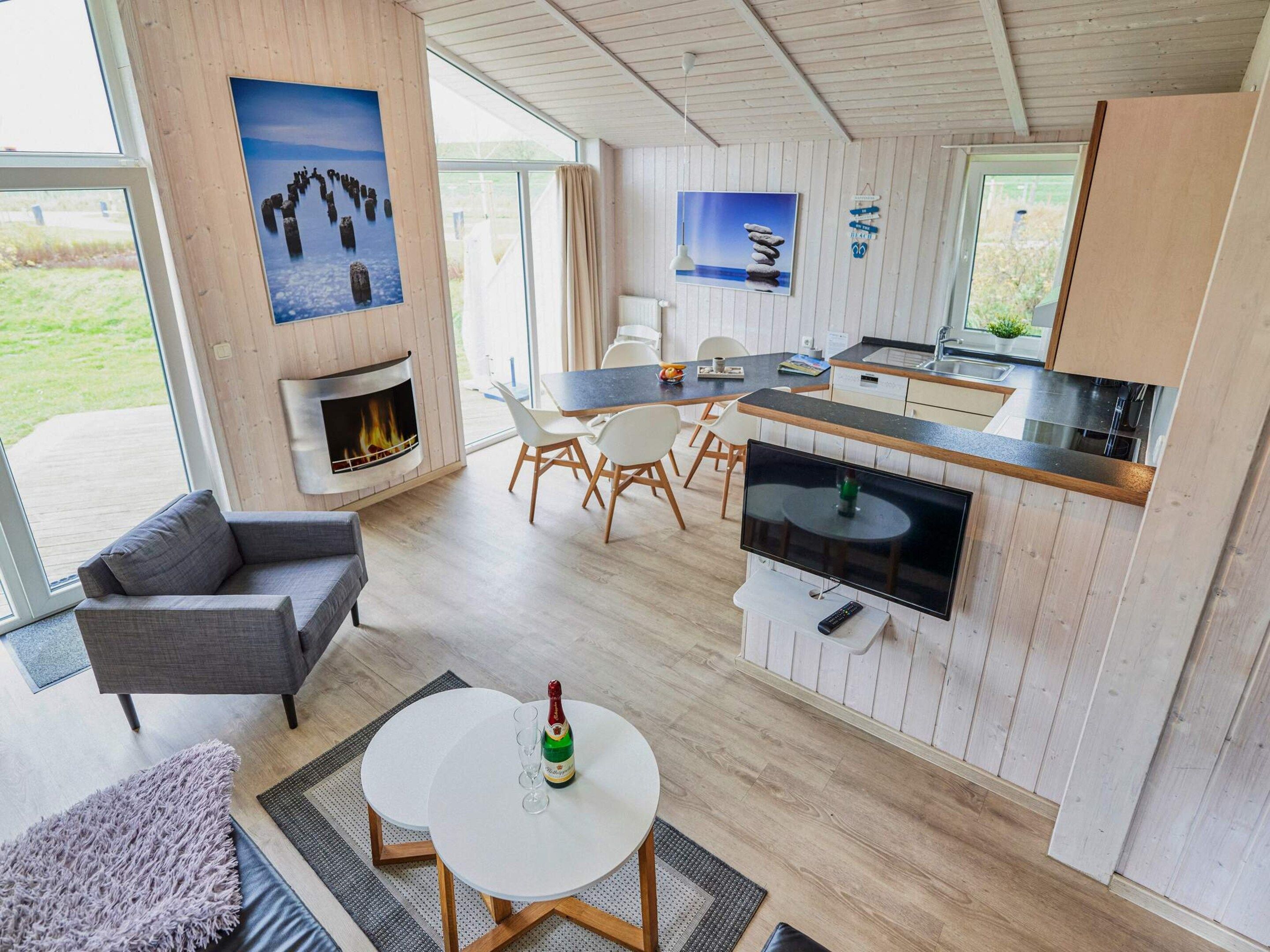 Ein modernes Interieur mit Kamin, Essbereich, Küche und großen Fenstern.