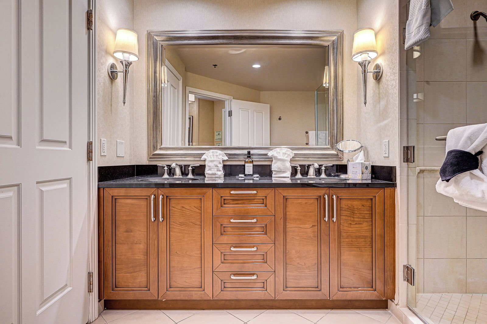 A bathroom with a double sink, wooden cabinets, and a large mirror.