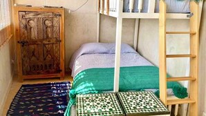 A bunk bed with a ladder, a wooden wardrobe, and a colorful painting on the wall. - Taghazout ocean view (Taghazout)