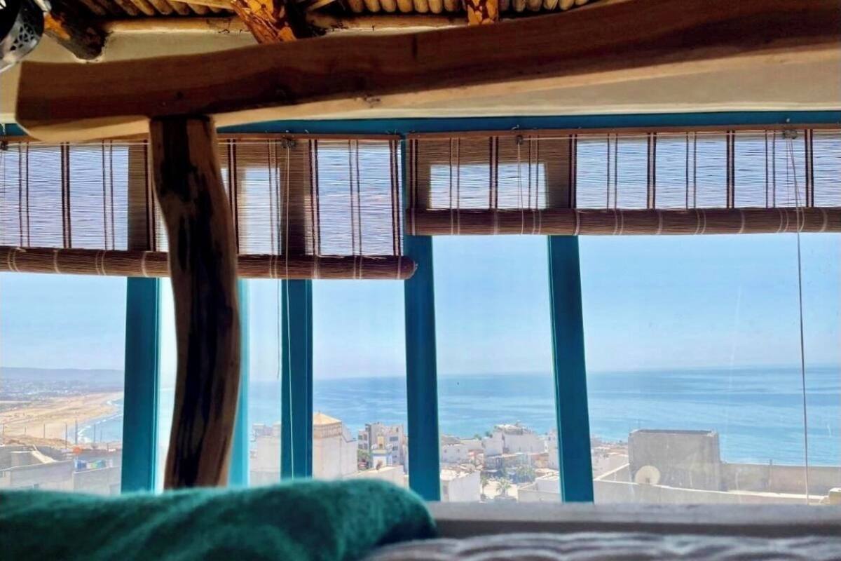 A room with a view of the sea and a cityscape.