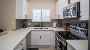 A modern kitchen with white cabinets, a stainless steel range, and a built-in oven.