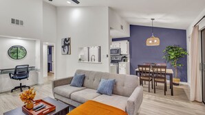 A modern living room with a sofa, coffee table, and dining area. - Newly Renovated Condo - Deck, Pet-Friendly, WFH (Austin)